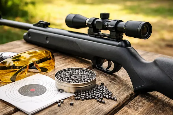 Vzduchovka pre začiatočníka s puškohľadom, diabolkami a terčom na streleckom stole.webp